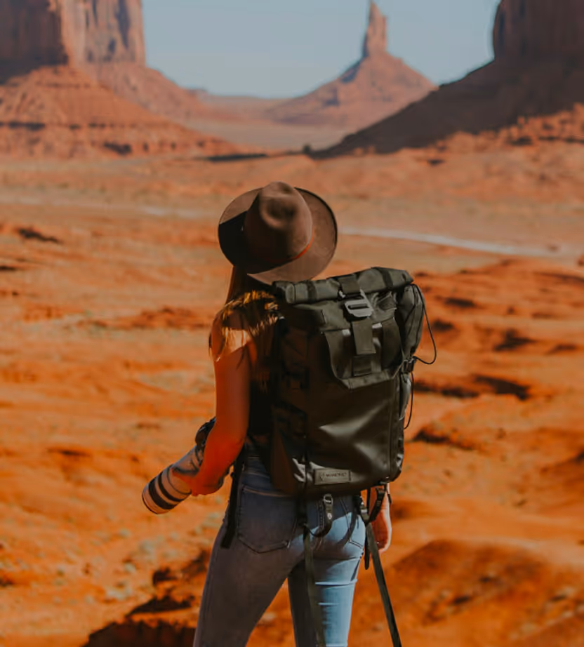 Hiker with backpack overlooking dramatic Monument Valley rock formations